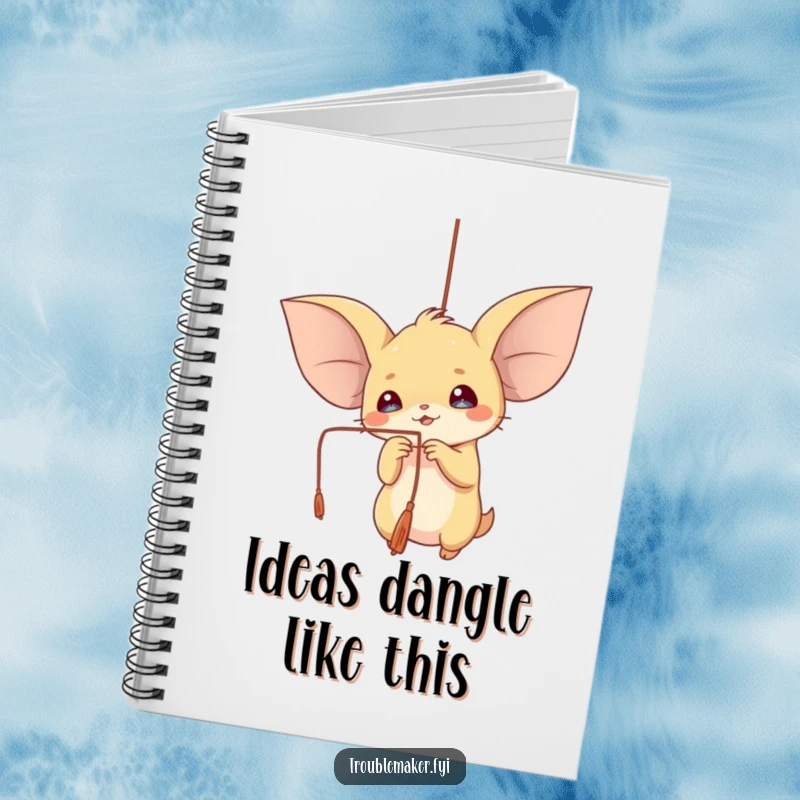 Funny notebook cover showing a creature with large ears playfully batting at a dangling string, ready for notes.