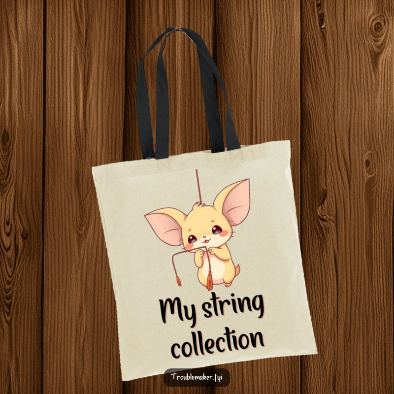 Funny tote bag showcasing a creature with big ears playfully batting at a dangling string, perfect for carrying essentials.